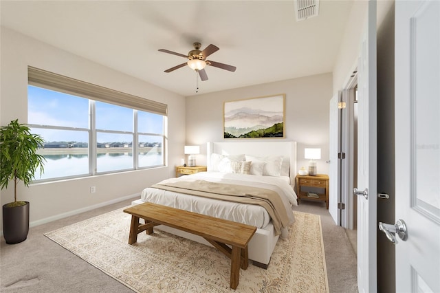 bedroom featuring a water view, light colored carpet, and ceiling fan