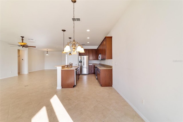 kitchen featuring decorative light fixtures, sink, a kitchen island with sink, ceiling fan, and stainless steel appliances