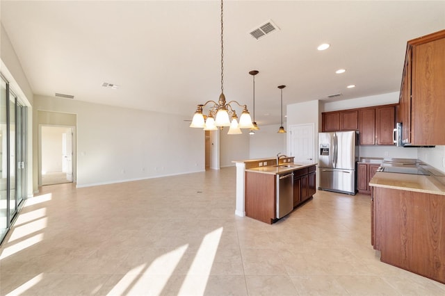 kitchen with appliances with stainless steel finishes, pendant lighting, sink, a chandelier, and a center island with sink