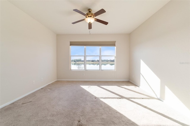 empty room with a water view, light colored carpet, and ceiling fan