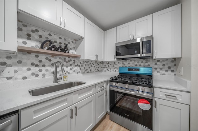 kitchen featuring stainless steel appliances, light stone countertops, sink, and white cabinets