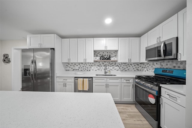 kitchen featuring sink, decorative backsplash, stainless steel appliances, and white cabinets