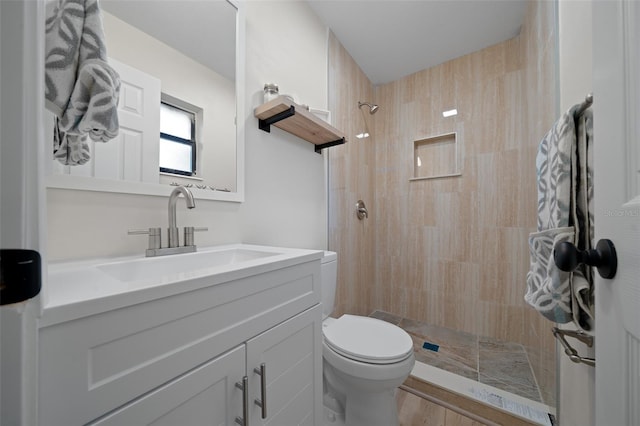 bathroom with vanity, a tile shower, and toilet