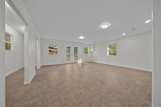 unfurnished living room with plenty of natural light, light tile patterned floors, and french doors