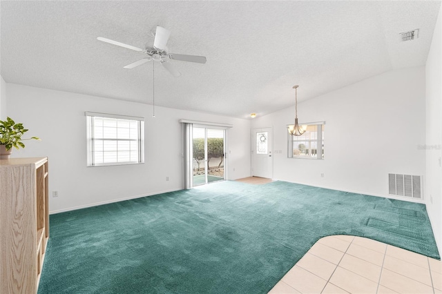 interior space with lofted ceiling, ceiling fan with notable chandelier, and a textured ceiling