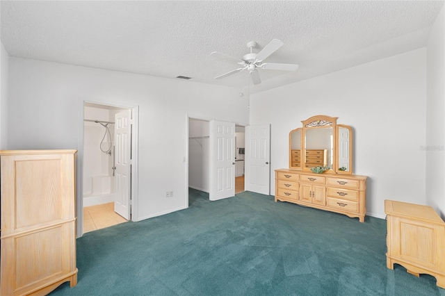 bedroom with connected bathroom, a spacious closet, a textured ceiling, and dark colored carpet