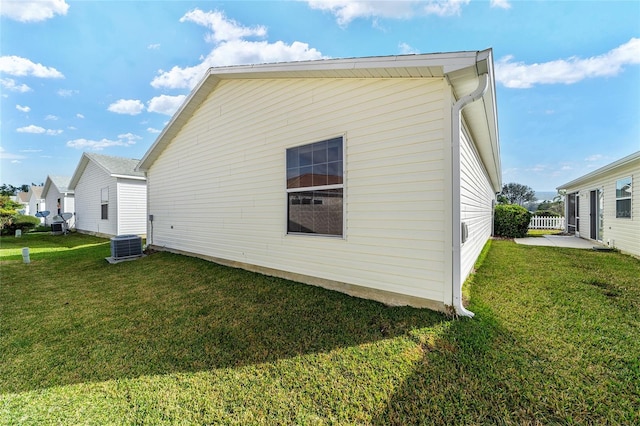 view of side of property with central AC unit and a lawn