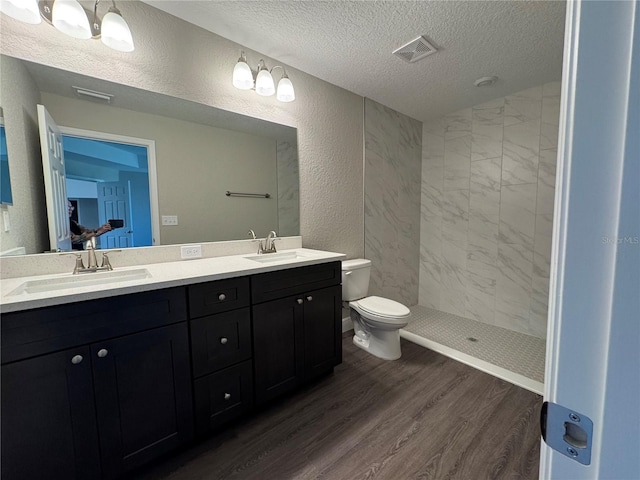 bathroom featuring a textured ceiling, wood finished floors, a textured wall, and a sink