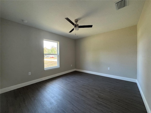 empty room with dark wood-style floors, visible vents, baseboards, ceiling fan, and a textured ceiling