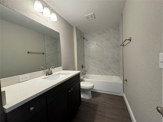 bathroom featuring toilet, vanity, a textured wall, wood finished floors, and a textured ceiling