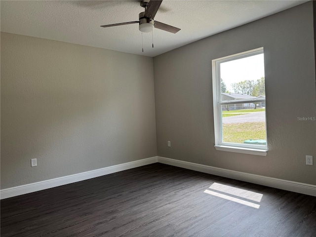 unfurnished room with baseboards, a textured ceiling, dark wood finished floors, and a ceiling fan