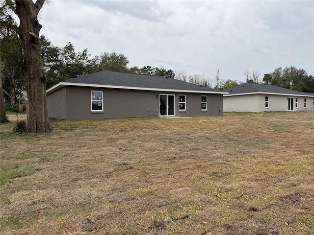 back of property featuring a yard and stucco siding