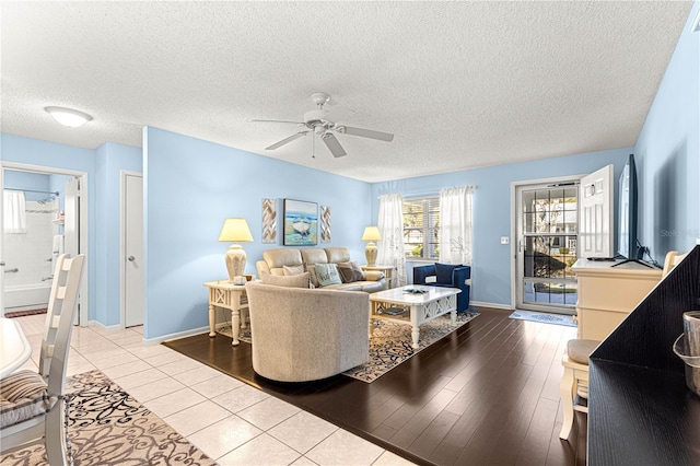 living room with a textured ceiling, light hardwood / wood-style flooring, and ceiling fan