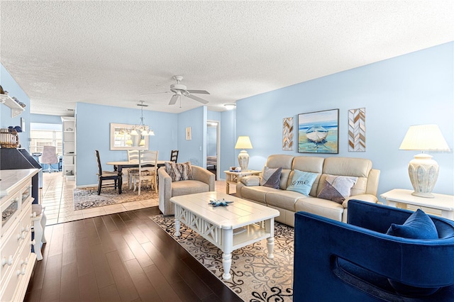 living room featuring ceiling fan, dark wood-type flooring, and a textured ceiling