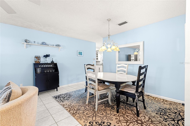 tiled dining area with ceiling fan with notable chandelier and a textured ceiling