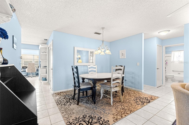 tiled dining area with a chandelier and a textured ceiling