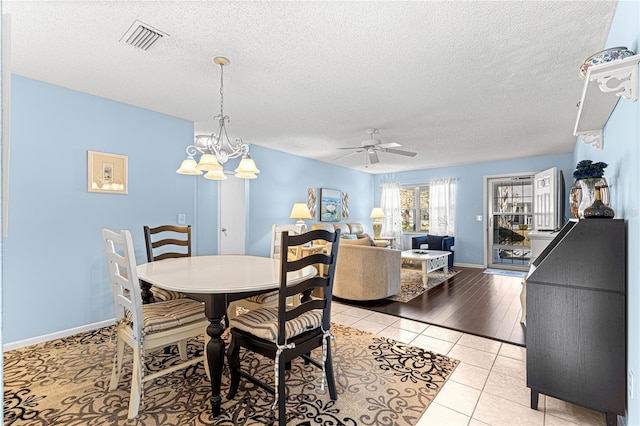 dining space with light tile patterned flooring, ceiling fan with notable chandelier, and a textured ceiling