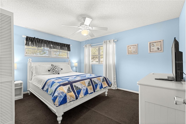 bedroom featuring ceiling fan, dark carpet, and a textured ceiling