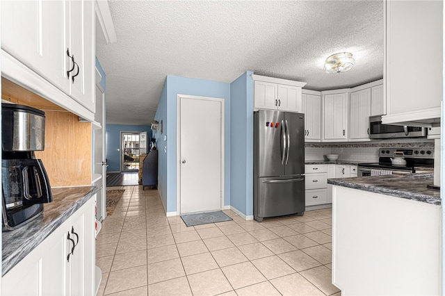 kitchen featuring light tile patterned flooring, white cabinetry, dark stone counters, stainless steel appliances, and backsplash