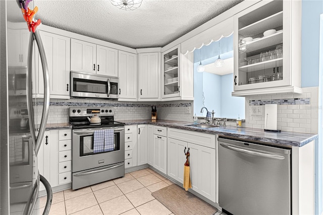 kitchen featuring sink, a textured ceiling, light tile patterned floors, appliances with stainless steel finishes, and white cabinets