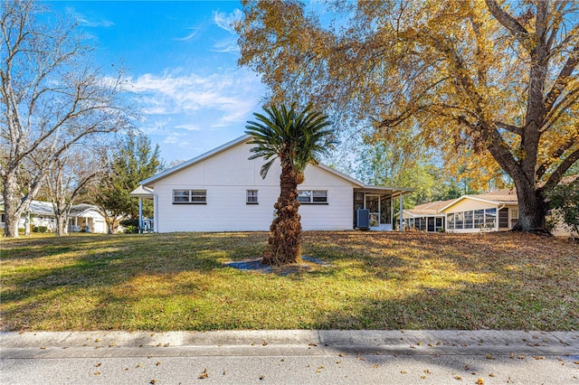 view of property exterior featuring a yard, a sunroom, and central air condition unit