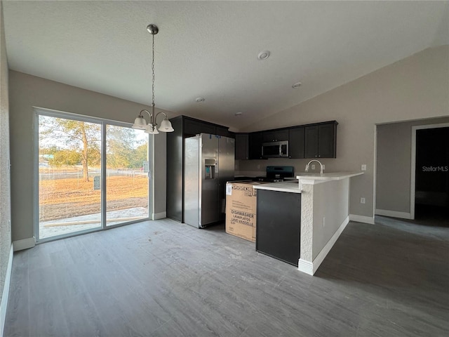 kitchen with lofted ceiling, a chandelier, hanging light fixtures, kitchen peninsula, and stainless steel appliances