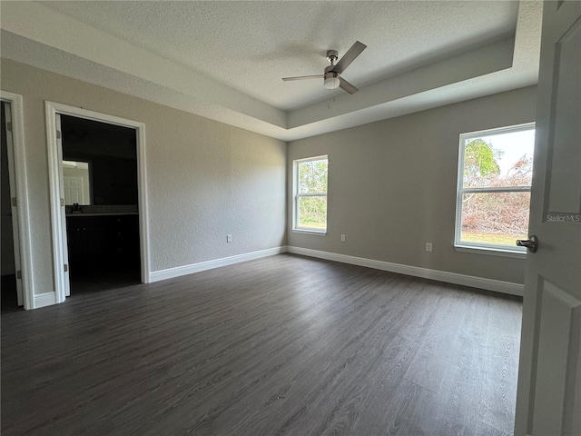 spare room featuring dark wood-style floors, a textured ceiling, baseboards, and a ceiling fan