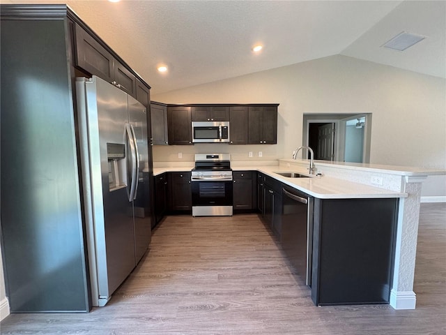 kitchen featuring visible vents, a peninsula, light wood-style flooring, a sink, and appliances with stainless steel finishes