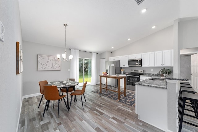 kitchen featuring sink, appliances with stainless steel finishes, white cabinets, decorative light fixtures, and dark stone counters