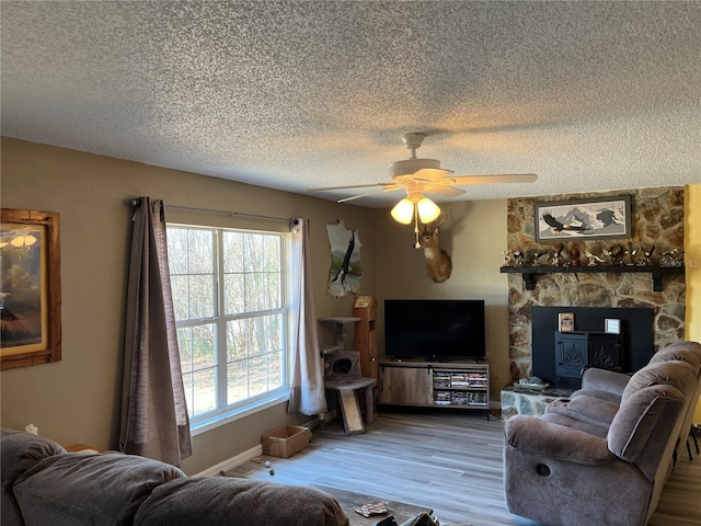 living room with a fireplace, wood-type flooring, a textured ceiling, and ceiling fan