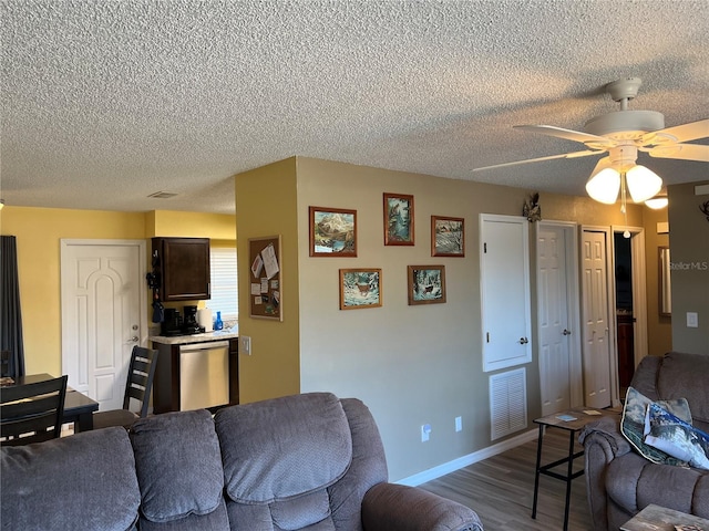 living room with ceiling fan, hardwood / wood-style flooring, and a textured ceiling