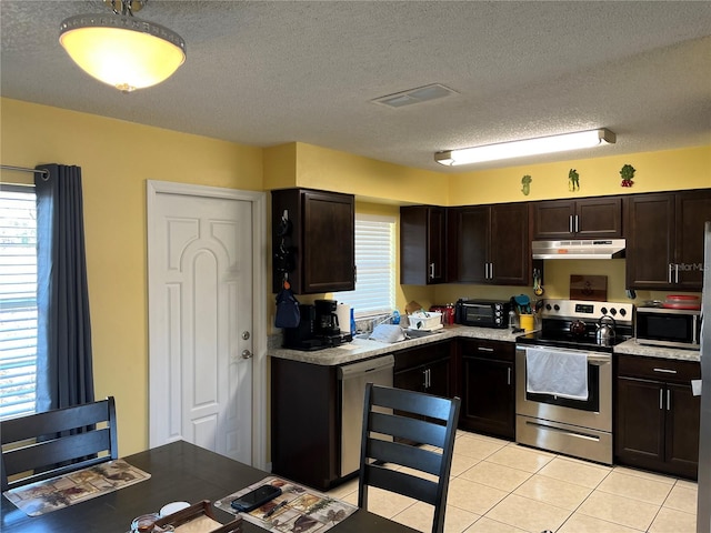 kitchen featuring light tile patterned floors, dark brown cabinets, a textured ceiling, and appliances with stainless steel finishes