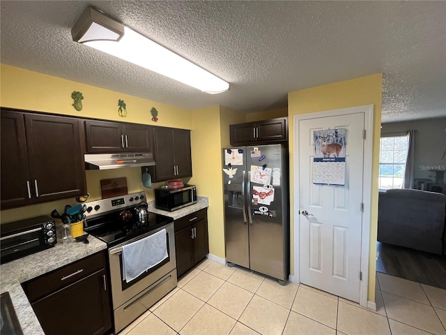 kitchen with dark brown cabinetry, stainless steel appliances, a textured ceiling, and light tile patterned floors