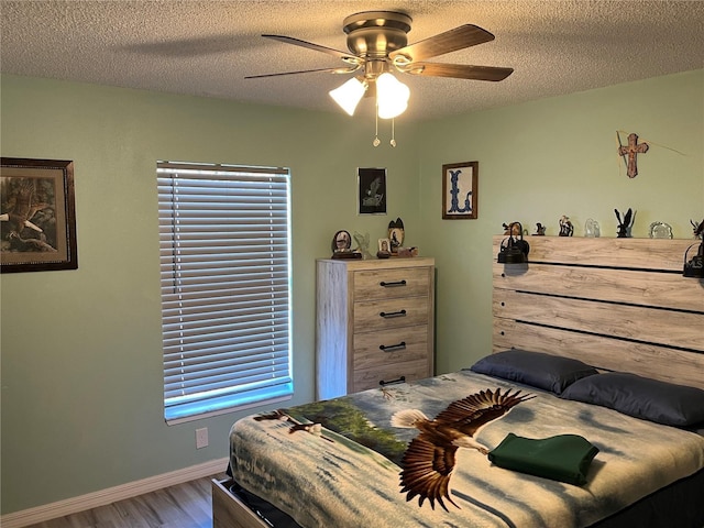 bedroom featuring hardwood / wood-style floors, a textured ceiling, and ceiling fan