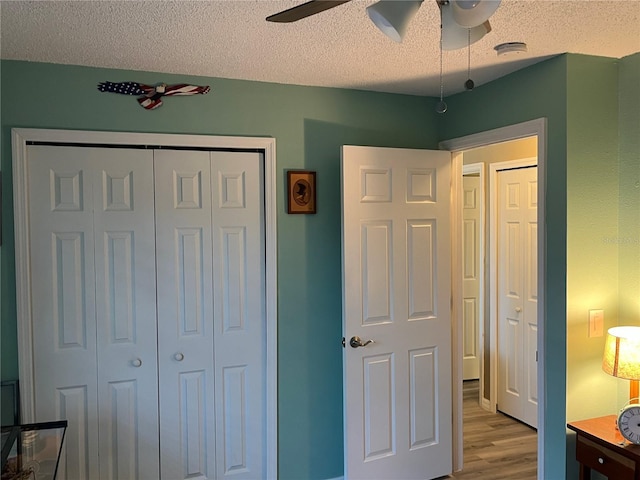 bedroom featuring ceiling fan, light hardwood / wood-style floors, a closet, and a textured ceiling