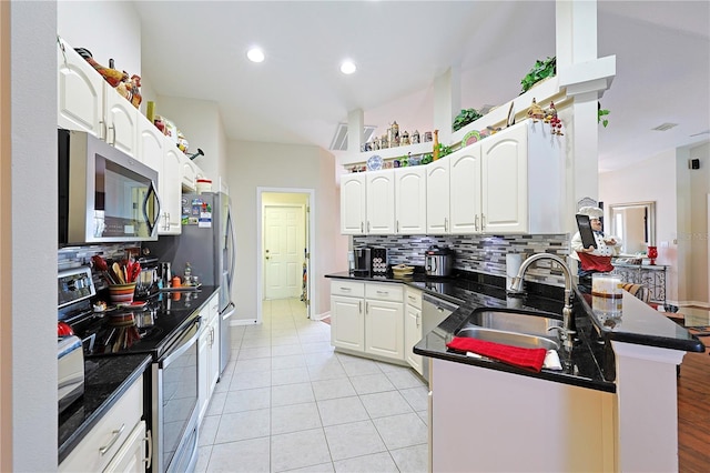 kitchen with appliances with stainless steel finishes, sink, white cabinets, decorative backsplash, and kitchen peninsula