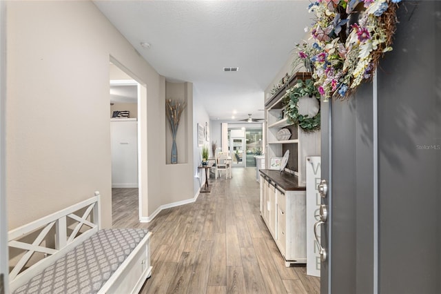 hall with light hardwood / wood-style flooring and a textured ceiling