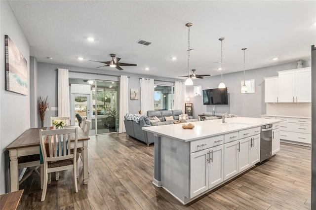 kitchen with sink, decorative light fixtures, hardwood / wood-style floors, a kitchen island with sink, and white cabinets