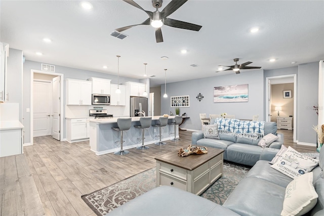 living room featuring ceiling fan and light hardwood / wood-style flooring