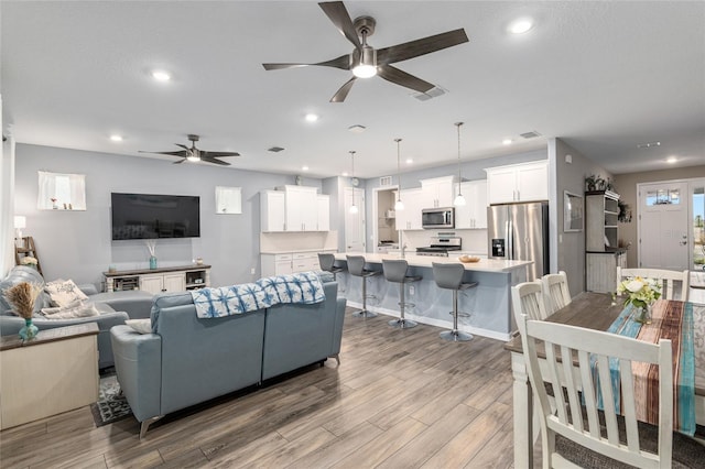 living room with ceiling fan and light wood-type flooring