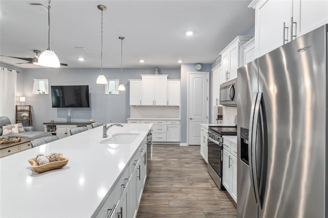 kitchen featuring sink, white cabinetry, hanging light fixtures, hardwood / wood-style flooring, and stainless steel appliances