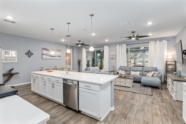 kitchen with white cabinetry, hanging light fixtures, a kitchen island with sink, stainless steel dishwasher, and light wood-type flooring