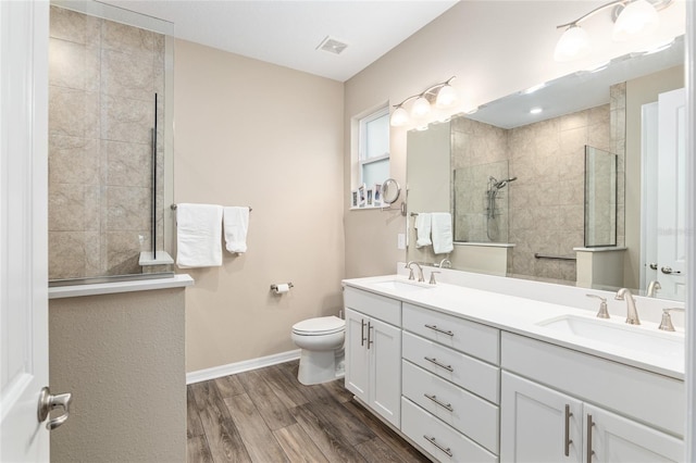 bathroom featuring vanity, hardwood / wood-style floors, toilet, and tiled shower