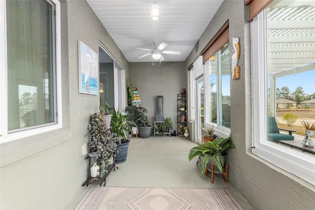 sunroom / solarium with ceiling fan and a wood stove