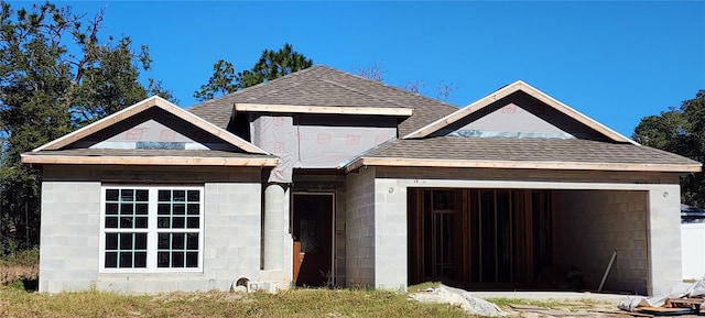 view of front of home featuring a garage, roof with shingles, and concrete block siding