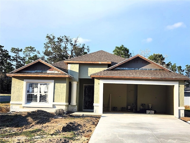 view of front of house with stucco siding, roof with shingles, concrete driveway, and an attached garage