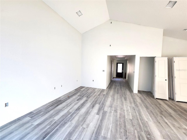 spare room with light wood-type flooring, high vaulted ceiling, and visible vents