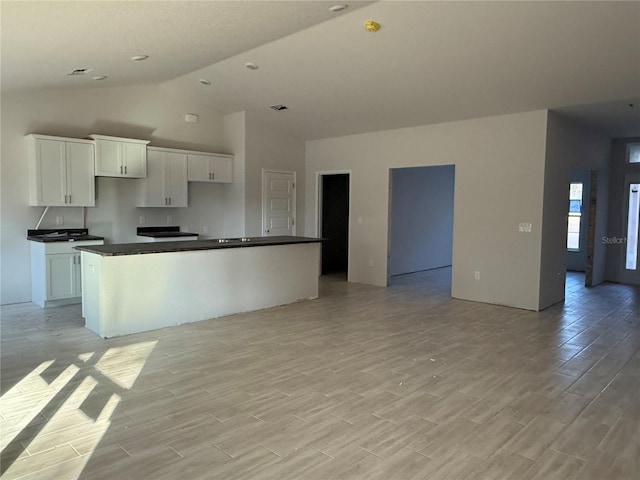 kitchen featuring white cabinetry, light hardwood / wood-style flooring, high vaulted ceiling, and a center island