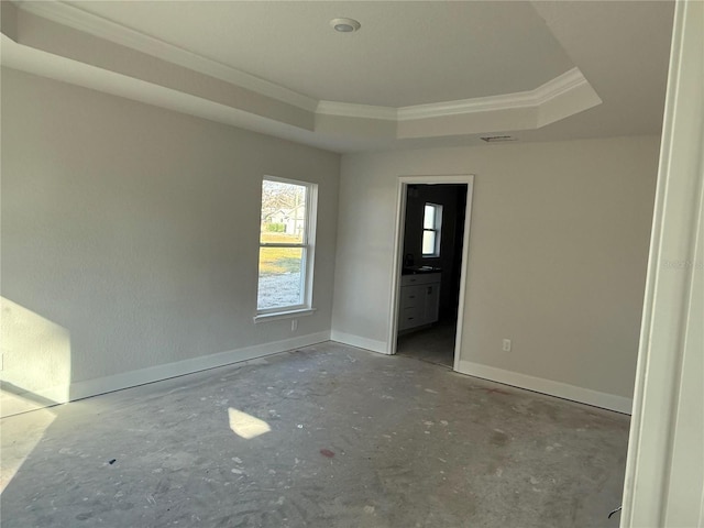 empty room with ornamental molding and a tray ceiling