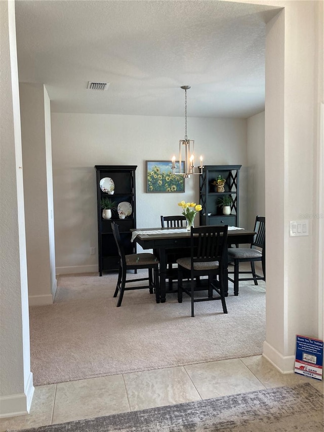 carpeted dining room with a chandelier and a textured ceiling